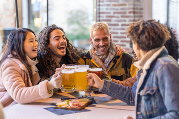 Young group multiracial friends in a pub drinking a beer together celebrating happy