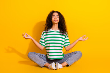 Full body portrait of nice young girl sit floor meditate wear striped t-shirt isolated on yellow color background