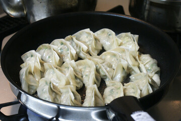 Japanese gyoza are pan-fried dumplings filled with minced pork, cabbage, garlic, and ginger, in thin dough. They are crispy outside, juicy inside, and served with a soy sauce and vinegar dip.