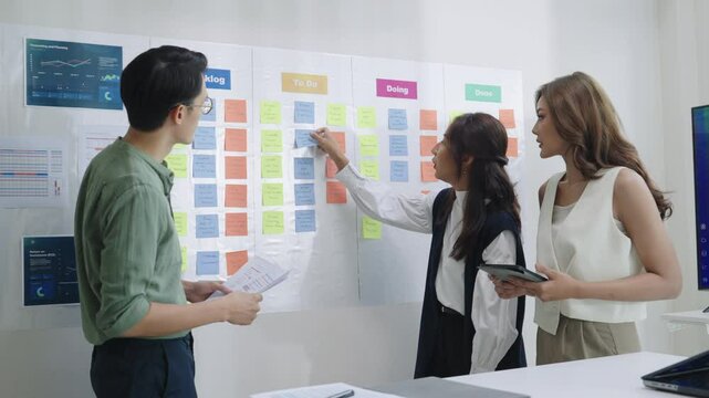 brainstorming session, using sticky notes on a task board (kanban) to organize ideas and workflow in a modern office