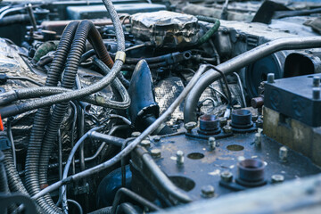 Close-up shot of a heavily used and dirty engine compartment. Showing various metal components, hoses, wires, and signs of wear and rust. 