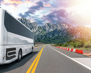 Obraz premium A white tourist bus travels along a picturesque mountain road.