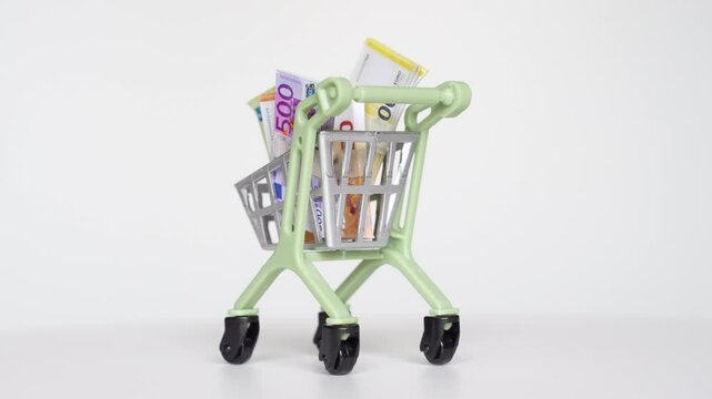 Euro cash a mini shopping cart, highlighting finance. Spin video.