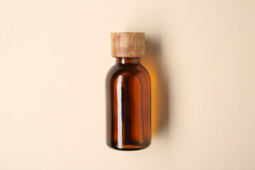 Essential oils in bottle on beige background, top view