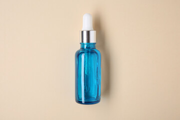 Essential oils in bottle on beige background, top view