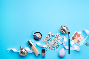 Flat lay composition with makeup products and Christmas decor on light blue background. Space for text