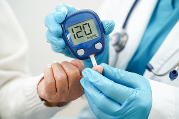 Asian doctor using digital glucose meter for check sample blood sugar level to treatment diabetes.