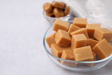 Tasty sweet caramel candies on light grey table, closeup. Space for text