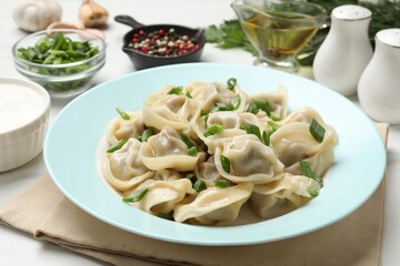 Delicious pelmeni with green onion served on white table, closeup