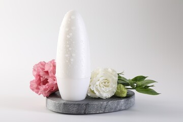 Roll-on deodorant and beautiful eustoma flowers on white background