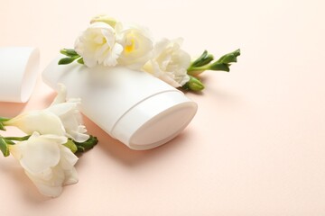 Solid deodorant and beautiful eustoma flowers on beige background, closeup
