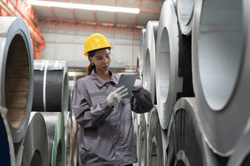Metalwork manufacturing, warehouse of raw materials. Woman factory worker inspecting quality rolls...