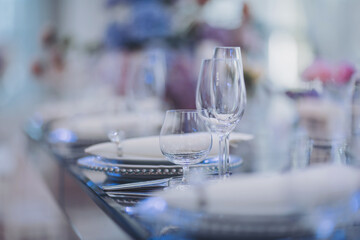 Flowers and candles on table. blue and white flowers decorate the table. Beautiful table set with glasses, plates, candles and flowers for a festive event, party or wedding reception.
