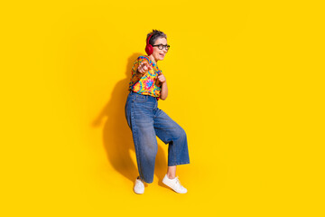 Full size photo of nice aged lady headphones point fingers you wear t-shirt isolated on yellow color background