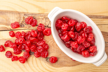 Dried pitted cherries in a white ceramic plate on a wooden table, macro. top view