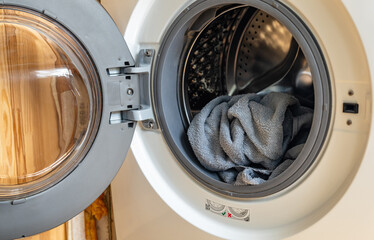 Laundry lies in washing machine with open door. Cleaning and house cleaning.