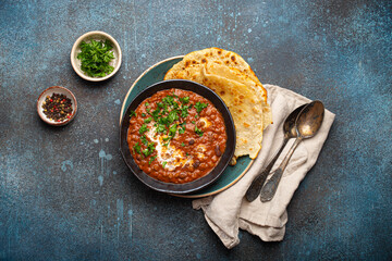 Traditional Indian Punjabi dish Dal makhani with lentils and beans in black bowl served with naan...