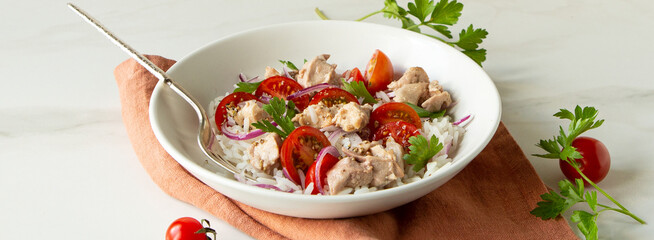 bowl of salad with rice, cod liver and cherry tomatoes on light table