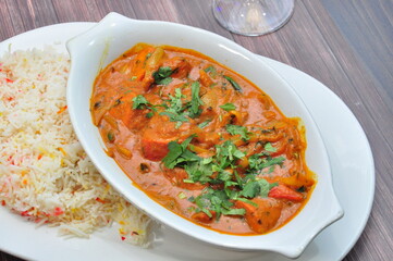 Creamy curry served in an elegant dish, garnished with fresh coriander served with a side of fluffy aromatic rice