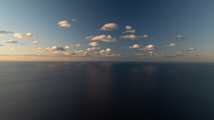 Fototapeta premium Under a blue sky dotted with clouds, a sizable expanse of water houses a solitary boat