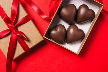 Gift box with heart-shaped chocolates on a vibrant red background, Valentine's day celebration