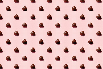 Heart-shaped chocolate pieces arranged on a pink background, Valentine's day backdrop