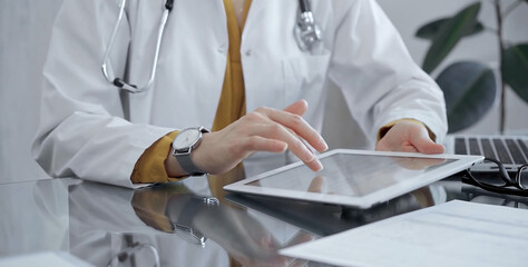 Doctor woman using tablet on the glass desk in medical office. Medicine and health care