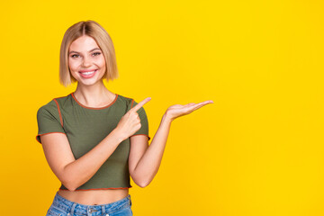 Photo of nice cute girl with bob hair dressed khaki t-shirt directing at object on palm empty space isolated on yellow color background