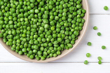 Fresh green peas on white wooden table, top view