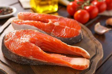 Board with fresh salmon steaks on table, closeup