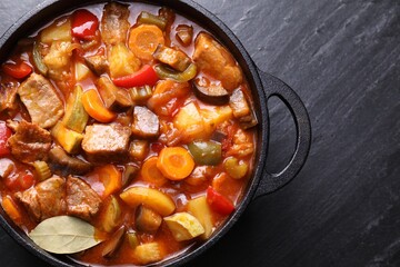 Delicious stew with vegetables in pot on gray textured table, top view