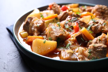 Delicious stew with vegetables on black table, closeup