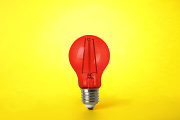 One red light bulb on yellow background