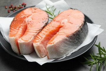 Fresh raw salmon steaks and spices on grey table, closeup