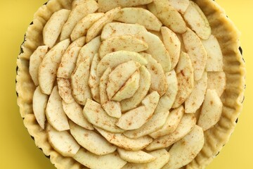 Raw homemade apple pie on yellow background, top view