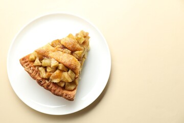 Slice of homemade apple pie on beige background, top view. Space for text