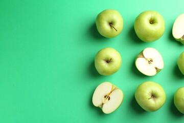 Flat lay composition with whole and cut apples on green background. Space for text