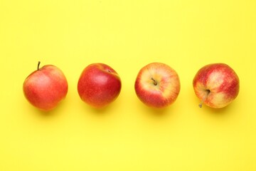Red apples on yellow background, flat lay