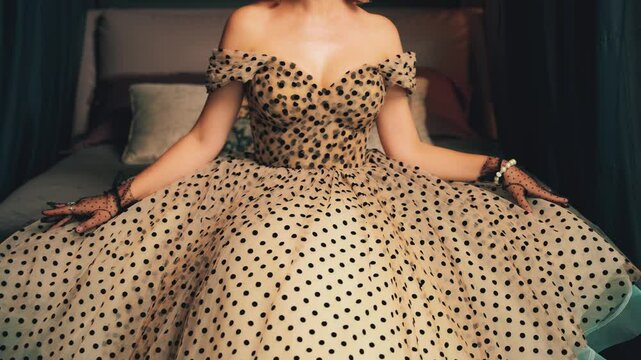 retro lady beauty woman pinup sitting on bed. old-fashioned sexy Vintage polka dot white black beige dress. Girl fashion model bare open shoulders elegant neckline cropped face 30s pin-up old style