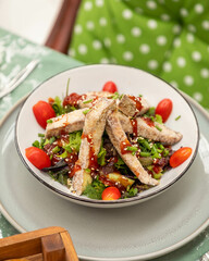 Delicious salad with breaded chicken, avocado, tomatoes and sesame seeds on a plate