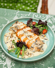 Sliced grilled chicken breast with creamy mushroom sauce, served on turquoise plate