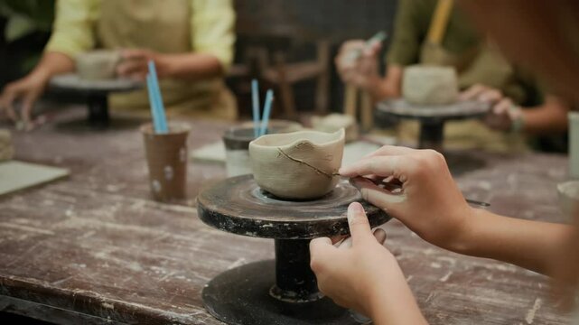 Cropped shot of unrecognizable artisan carefully carving intricate patterns into clay bowl at pottery workshop