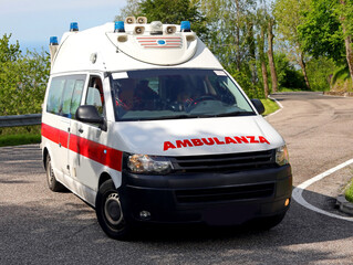 ambulance van with red italian text on the hood rushing down the street during an emergency