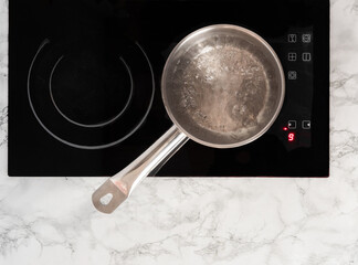 Boiling water in a ladle. Pot on top of the stove with boiling water. View from above.