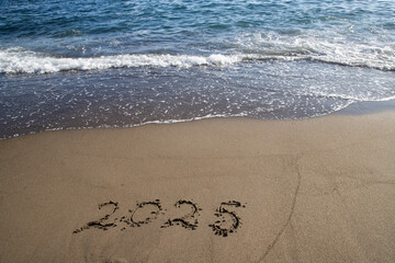 tropical New Year 2025 written in sand on the beach