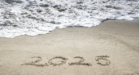 tropical New Year 2025 written in sand on the beach