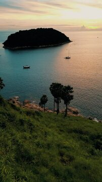 Vertical Video - Aerial View of Ocean with Green Meadows and Island in the Distance during sunset