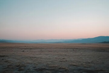 Fototapeta premium A serene landscape at dusk, featuring vast plains and distant mountains under a pastel sky.