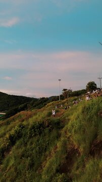 Vertical Video - Tourists on Coastal Meadows with Windmill in Background &ndash; Aerial View