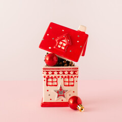 Little ceramic house full of Christmas decoration balls and pine cones. Xmas background. 